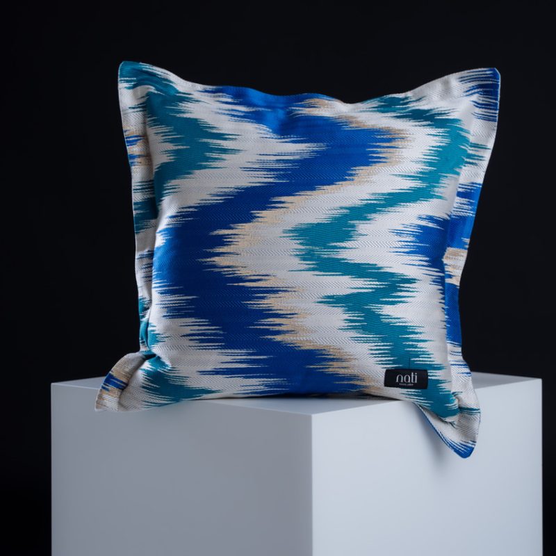 Nati Luxury Pillow Kissen 'Zigzag – Sapphire' – Zickzack-Ikat-Muster in Saphirblau, Türkis und Cremeweiß, freigestellt auf einem Podest